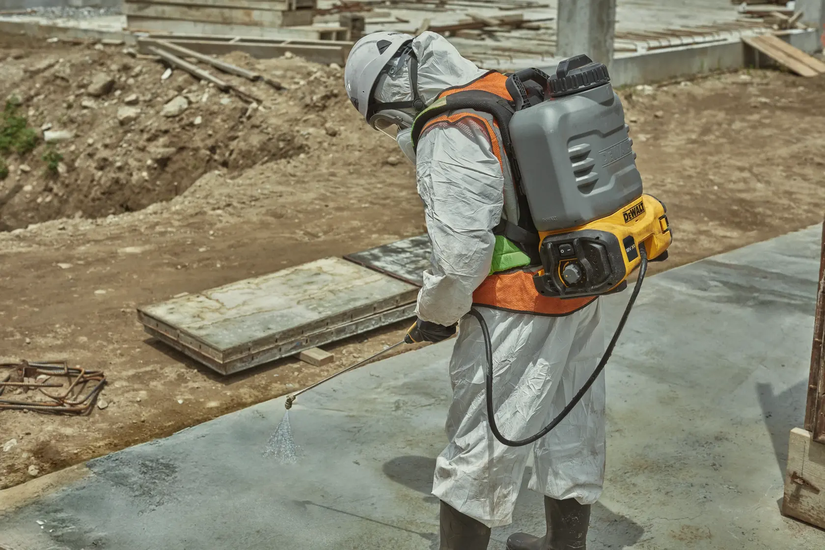 Worker uses DEWALT DCCS1100N-XJ, DCCS1100N sprayer at construction site. Photography product category.