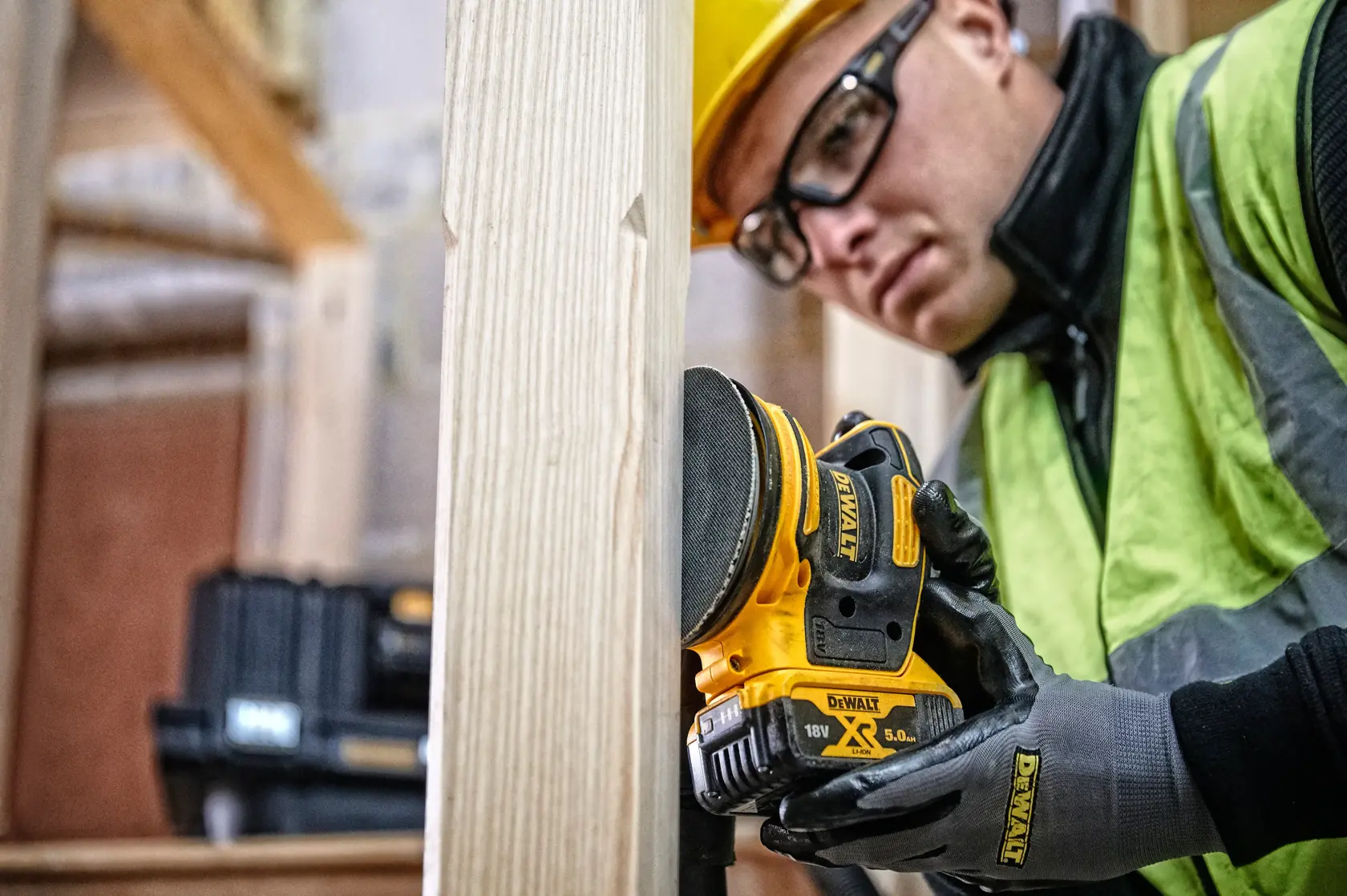 DEWALT DCW210, DCW210D1 sander used on wood by worker; gloves and tool box visible.